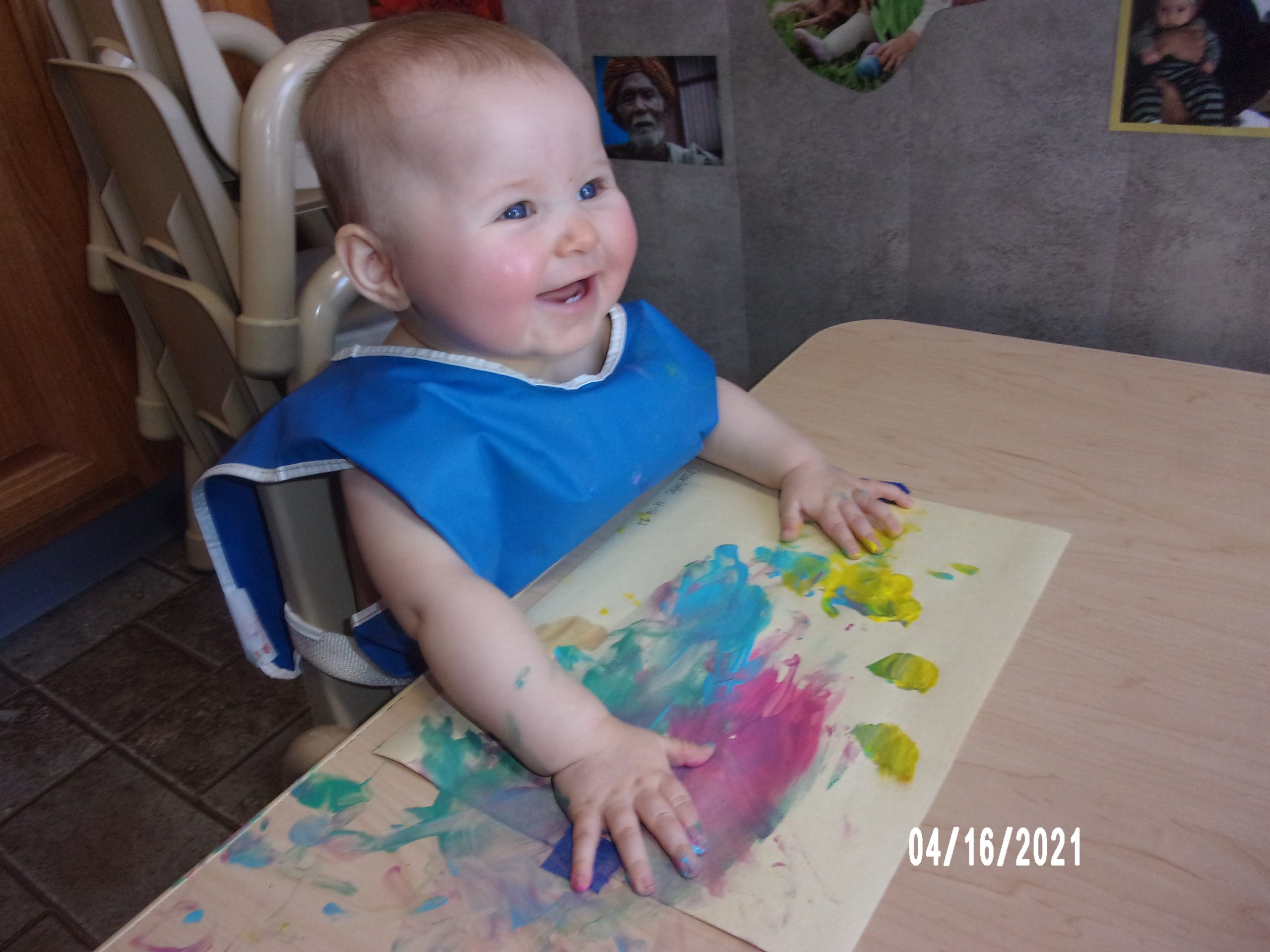 An infant smiling during a finger-painting activity