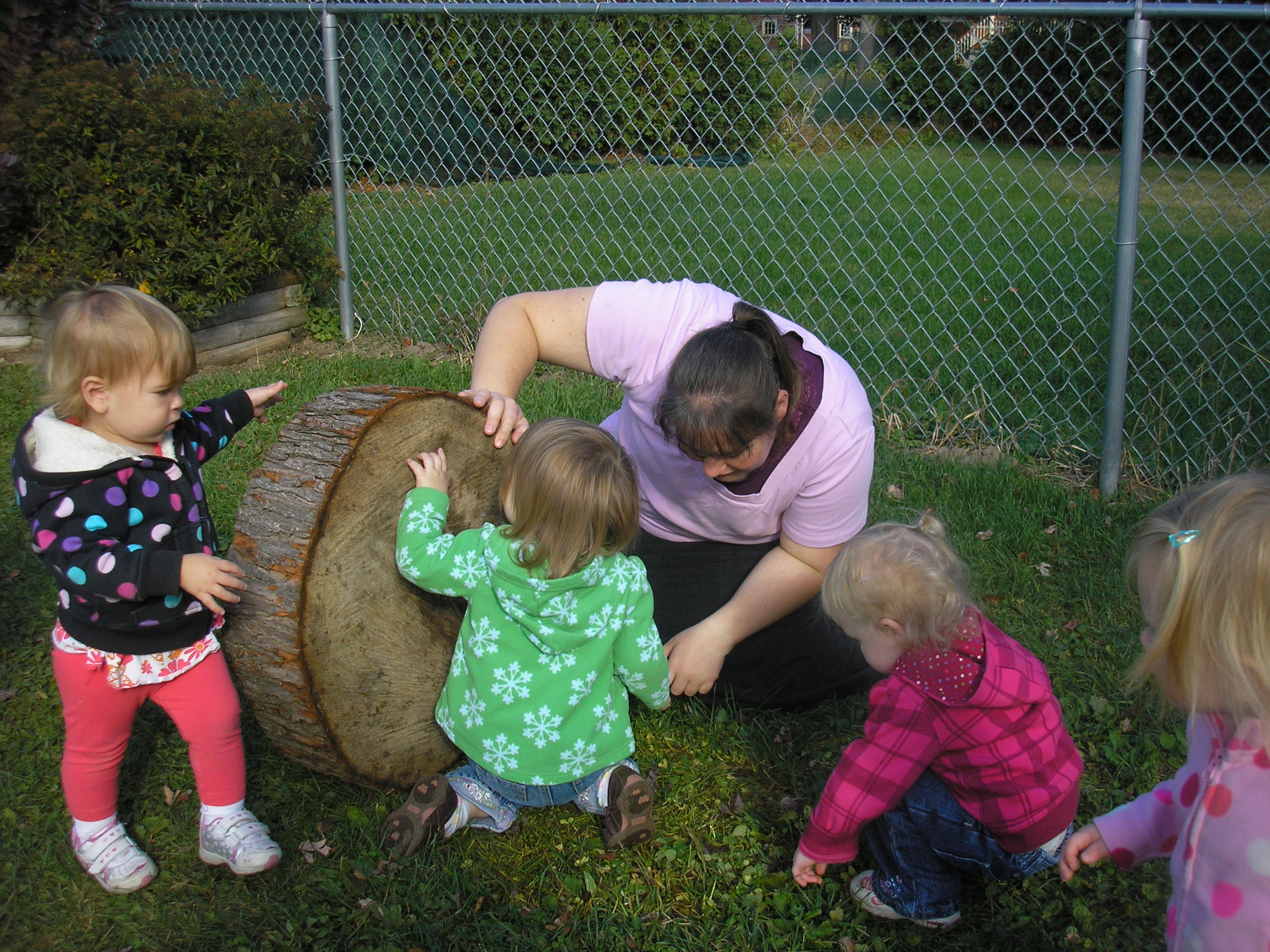 A teacher guiding young children as they explore outdoors